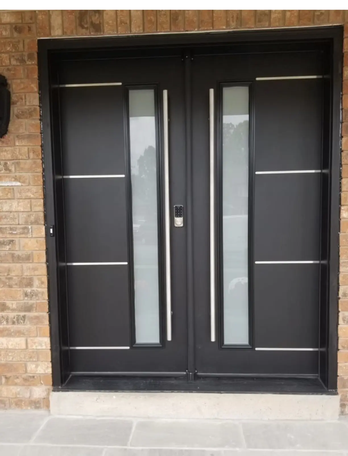 Modern Black Front Door with Full Glass Panel and Side Lite – Contemporary Entry Door Design Sleek modern black front door with three-panel frosted glass insert and matching side lite, installed in a brick and stone exterior entryway under a covered porch.