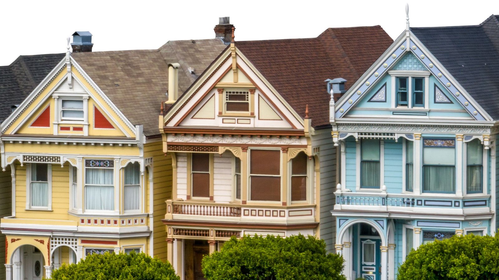 Row of colorful Victorian-style homes with ornate architectural details, decorative trim, and large windows, showcasing classic heritage design.